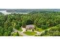 Stunning aerial view of brick home surrounded by lush trees and overlooking a scenic lake at 106 Pier Point Dr, Stony Point, NC 28678
