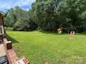 Expansive backyard with a playset and mature trees offering ample space for recreation and relaxation at 232 Harmony Hills Dr, Catawba, SC 29704