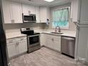 Modern kitchen with white cabinets, stainless steel appliances, stone countertops, and hardwood floors at 232 Harmony Hills Dr, Catawba, SC 29704