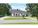 Exterior elevation of a house with gray roof, white siding, front porch, black door and window trim, and landscaped garden at 307 W Sunset Dr, Monroe, NC 28112