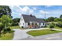Exterior elevation of a house with gray roof, white siding, front porch, black door and window trim, and landscaped garden at 307 W Sunset Dr, Monroe, NC 28112