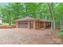 A detached garage with brick construction featuring a brown door and brick-paved driveway at 3985 Well Rd, Mint Hill, NC 28227