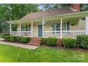 Inviting front porch with a swing, hanging plants, and well-maintained landscaping at 6706 Farrington Ln, Charlotte, NC 28227