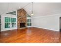 Spacious living room featuring hardwood floors, a stone fireplace, and large windows for natural light at 7613 Happy Hollow Dr, Mint Hill, NC 28227