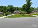 Well-manicured front lawn enhances the curb appeal of this charming brick home with lush landscaping at 11646 Hidden Forest Ln, Davidson, NC 28036