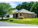 A beautiful, well-kept brick home with a two-car garage and lush landscaping on a sunny day at 141 Aberdeen Dr, Troutman, NC 28166