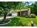 A well-maintained brick home with a manicured lawn, lush landscaping, and a two-car garage at 141 Aberdeen Dr, Troutman, NC 28166
