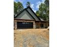 Newly constructed home with stone accents, a black garage door, and copper-colored gutters at 1923 Fairfield Rd, Mount Gilead, NC 27306