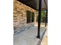 A covered porch is adorned with stacked stone, sleek windows, and dark stained wooden posts at 1923 Fairfield Rd, Mount Gilead, NC 27306