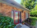 Inviting front entry with a red door, decorative plants, and charming accents at 2104 Farmbrook Dr, Statesville, NC 28625