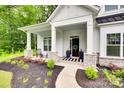 Inviting front porch with stone pillar bases, seating, and a stylish striped doormat at 2324 Loire Valley Dr, Indian Land, SC 29707