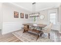 Formal dining room featuring a wooden table, wainscoting, modern light fixture and neutral decor at 2732 Berkhamstead Cir, Concord, NC 28027