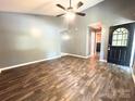 Open living room with wood floors, ceiling fan, black door and neutral walls, creating a versatile living space at 3051 Dairy Farm Dr, Monroe, NC 28110