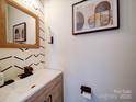Stylish half bathroom featuring modern vanity, bold wallpaper, and decorative mirror and artwork at 5121 Arbordale Way, Mount Holly, NC 28120