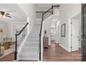 Inviting two-story entryway featuring a staircase with black and white railings, hardwood floors and neutral walls at 6803 Augustine Way, Charlotte, NC 28270