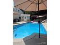 Sparkling blue pool with sun umbrellas, shed, and inviting lounging areas for outdoor relaxation and enjoyment at 7700 Antique Cir, Waxhaw, NC 28173