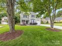 A well-maintained lawn surrounds this home with mature trees, bushes, and a driveway leading to the garage at 9908 Park Springs Ct, Charlotte, NC 28210