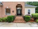 Inviting brick entryway with a decorative front door, elegant iron railings, and lush landscaping at 172 Hunters Hill Dr, Statesville, NC 28677