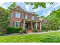 Beautiful red brick two-story home with a covered front porch and lush landscaping at 2004 Viscount Dr, Matthews, NC 28104