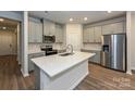 A modern kitchen with stainless steel appliances, gray cabinets, and a stylish island with a sink at 2142 Sunflower Cir, Newton, NC 28658
