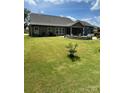Expansive backyard featuring lush green grass, a cozy screened porch, and a stone patio at 5332 Pembrey Dr, Denver, NC 28037