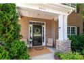 Inviting front porch with a wreath, cozy seating, and brick and stone accents at 8909 Savannah Rd, Harrisburg, NC 28075