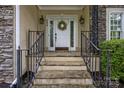 Inviting front entrance with stone steps, black iron railings, and a decorative wreath on the white door at 9038 Sandpiper Dr, Charlotte, NC 28277