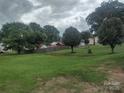 Expansive green backyard with mature trees, wooden fence and several houses in background at 1017 W C St, Kannapolis, NC 28081