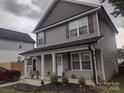 Two-story home featuring a covered porch, grey siding, and neat landscaping at 1017 W C St, Kannapolis, NC 28081