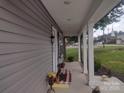 Charming front porch with gray siding, white pillars, and a view of the lawn and neighboring church at 1017 W C St, Kannapolis, NC 28081