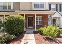 Close-up of a brick front entrance with a dark wood door and manicured shrubs at 12516 Hennigan Place Ln, Charlotte, NC 28214