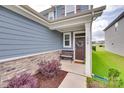 Inviting front porch with a stone foundation, bench, manicured landscaping, and decorated entry door at 150 Bezelle Ave, York, SC 29745