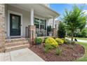 Charming front porch with brick columns, black railing, and landscaped garden, creating an inviting entrance to the home at 17231 Rider Wood Ln, Charlotte, NC 28278