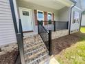 The inviting front porch features brick steps, a black metal railing, and wood shutters, creating a warm welcome at 325 Jordan Ave, Salisbury, NC 28159