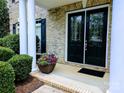 Close-up of a home's front porch with double doors, white columns, and beautiful flower display at 408 Presidio Dr, Rock Hill, SC 29732