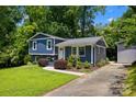 The blue split-level home boasts a well-maintained yard, mature trees, and updated landscaping at 6733 Candlewood Dr, Charlotte, NC 28210