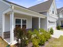 Inviting front porch featuring brick accents, landscaping, and gray vinyl siding at 117 Carmine Ct, Troutman, NC 28166