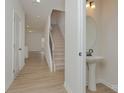 Bright entryway with wood-look floors, a staircase with a dark metal handrail, and a pedestal sink at 1266 Langston Ln, Salisbury, NC 28144