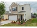 Charming two-story home with a two-car garage, manicured lawn, stone accents and neutral colored siding at 1266 Langston Ln, Salisbury, NC 28144