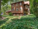Two-story home featuring brown siding and a well-manicured front yard with lush greenery and ivy at 3310 Windbluff Dr, Charlotte, NC 28277