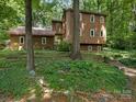 Two-story home nestled in the woods featuring brown siding and a well-manicured yard at 3310 Windbluff Dr, Charlotte, NC 28277
