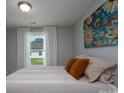 Cozy bedroom featuring a comfortable bed with decorative pillows, a colorful floral painting, and a window with sheer curtains at 360 Sexton St, Kannapolis, NC 28081