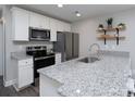 Well-lit kitchen with stainless steel appliances, white cabinets, granite countertops, and open shelving for decorative plants at 360 Sexton St, Kannapolis, NC 28081