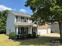 Well-manicured front yard with lush green grass and mature trees surrounding this two-story, brick and vinyl home at 5009 Brook Valley Run, Monroe, NC 28110
