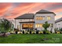 Stunning backyard view of the brick home with manicured lawn and mature landscaping at twilight at 920 Terramore Dr, Waxhaw, NC 28173