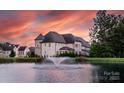 Picturesque view of the home across a pond with a fountain at sunset at 920 Terramore Dr, Waxhaw, NC 28173