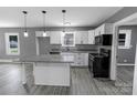 Bright kitchen with white cabinets, granite countertops, island with pendant lights, and black appliances at 1210 Cloninger Ave, Gastonia, NC 28052