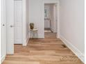 Hallway with wood-look flooring, white wainscoting, and view into kitchen and bathroom at 13414 Central Ave, Huntersville, NC 28078