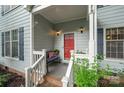 Cozy front porch featuring a bench, potted flowers, and a bright red front door, perfect for relaxing at 13416 Kintyre Ct, Matthews, NC 28105