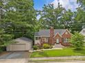 Full view of the brick home with garage, emphasizing curb appeal and surrounding greenery at 2005 Scott Ave, Charlotte, NC 28203